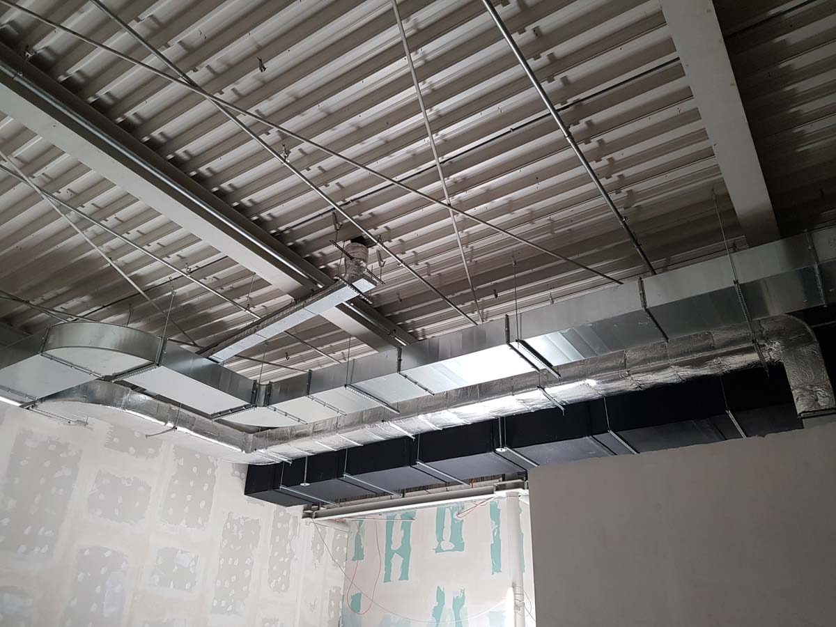Installation von Lüftungskanälen und Luftauslässen in einer Deckenkonstruktion für ein Bürogebäude.