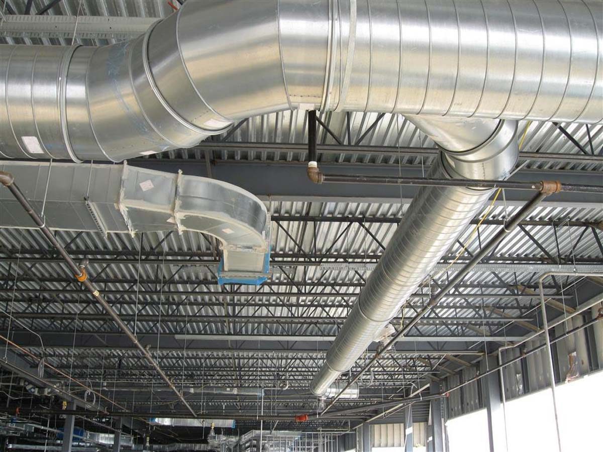 Installation von runden Wickelfalzrohren und rechteckigen Lüftungskanälen zur Be- und Entlüftung einer Lagerhalle.